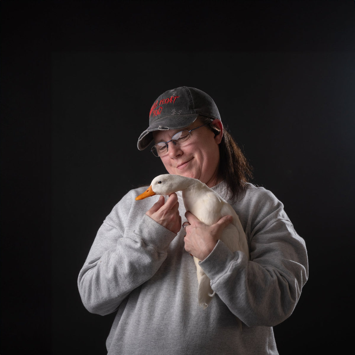 Person holding a duck against a black background