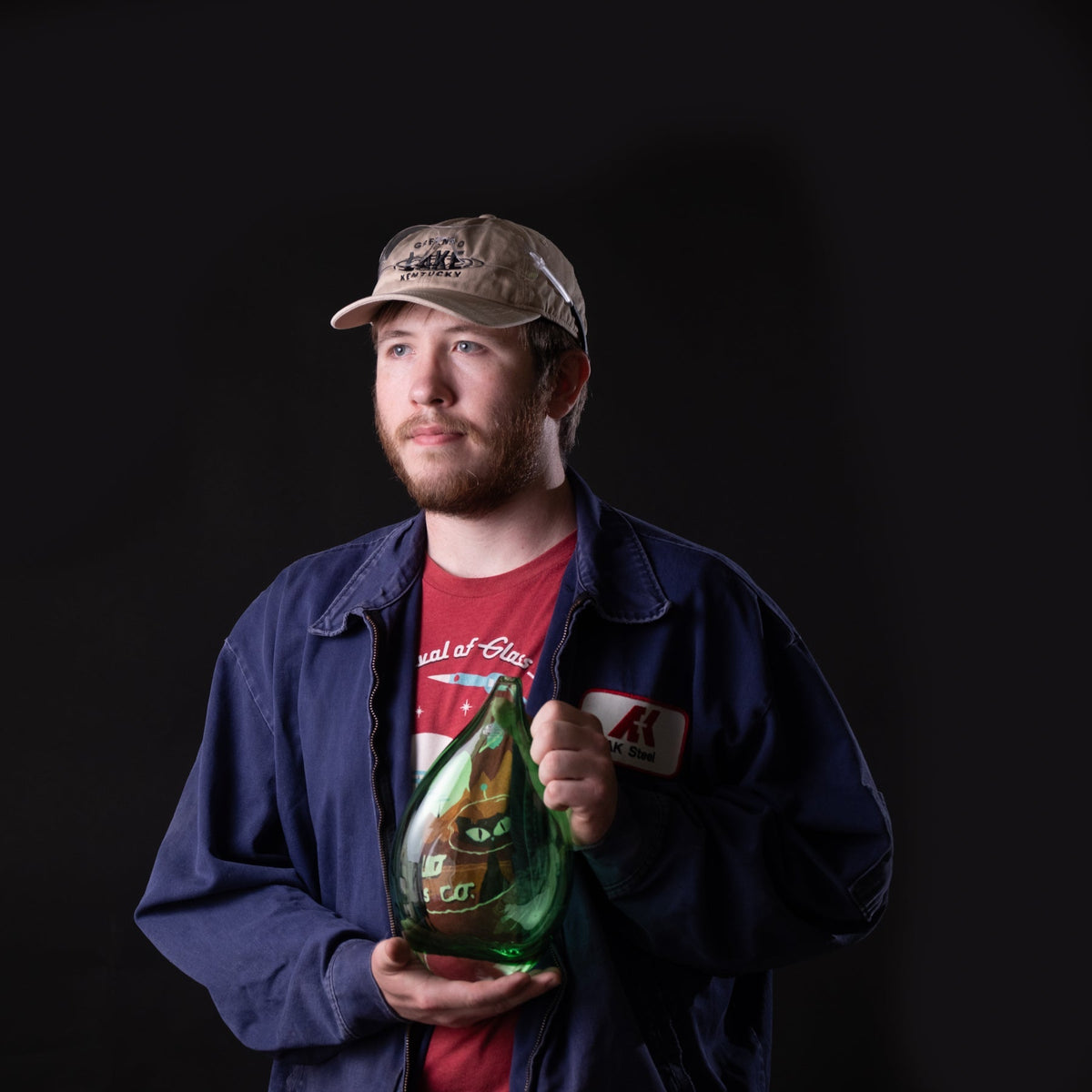 Man holding a green vase against a black background