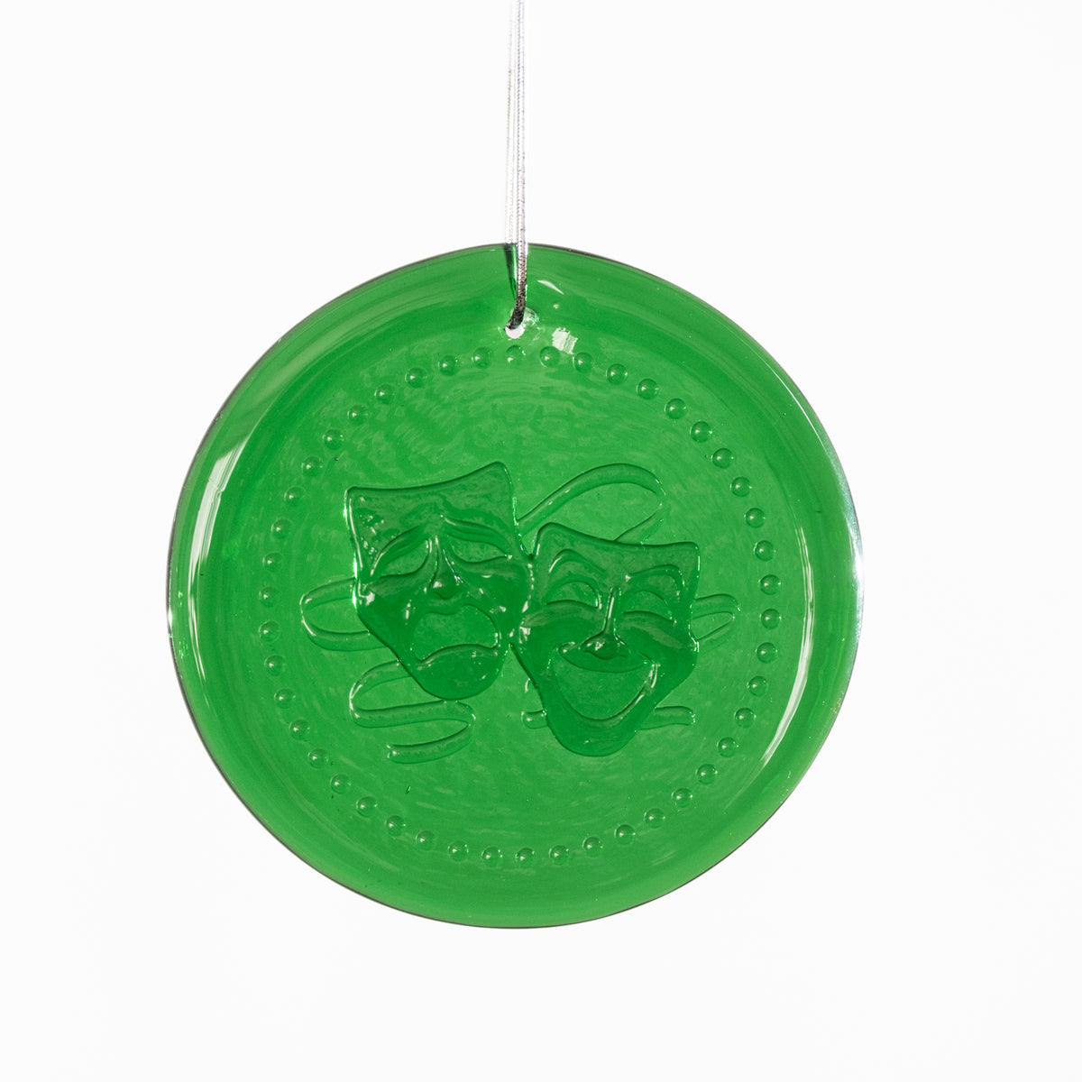 Green round decorative item with theater masks on a white background