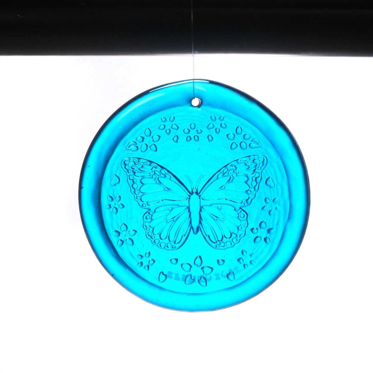 Turquoise circular decorative item with a butterfly design on a white background