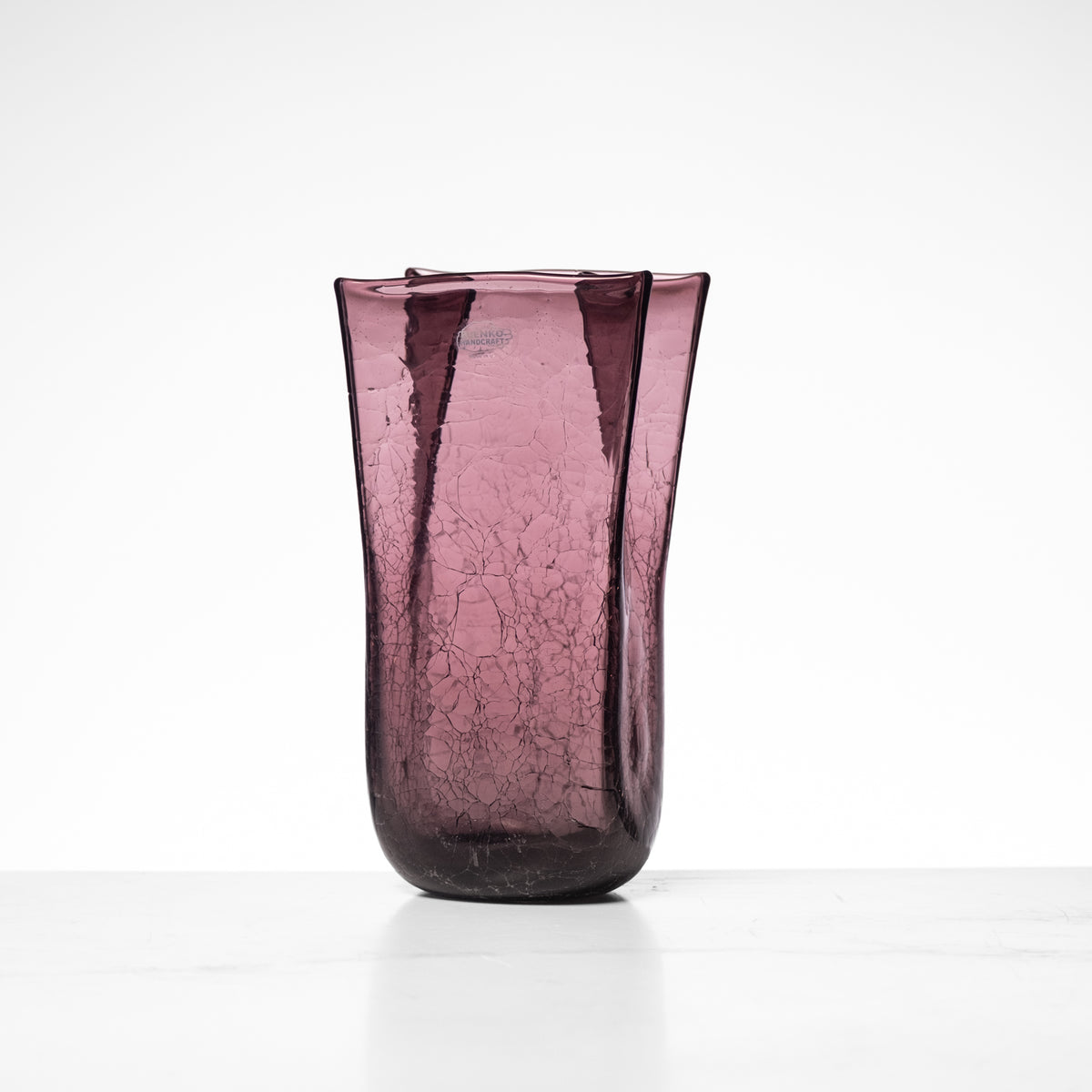 Purple glass vase with a textured surface on a white background