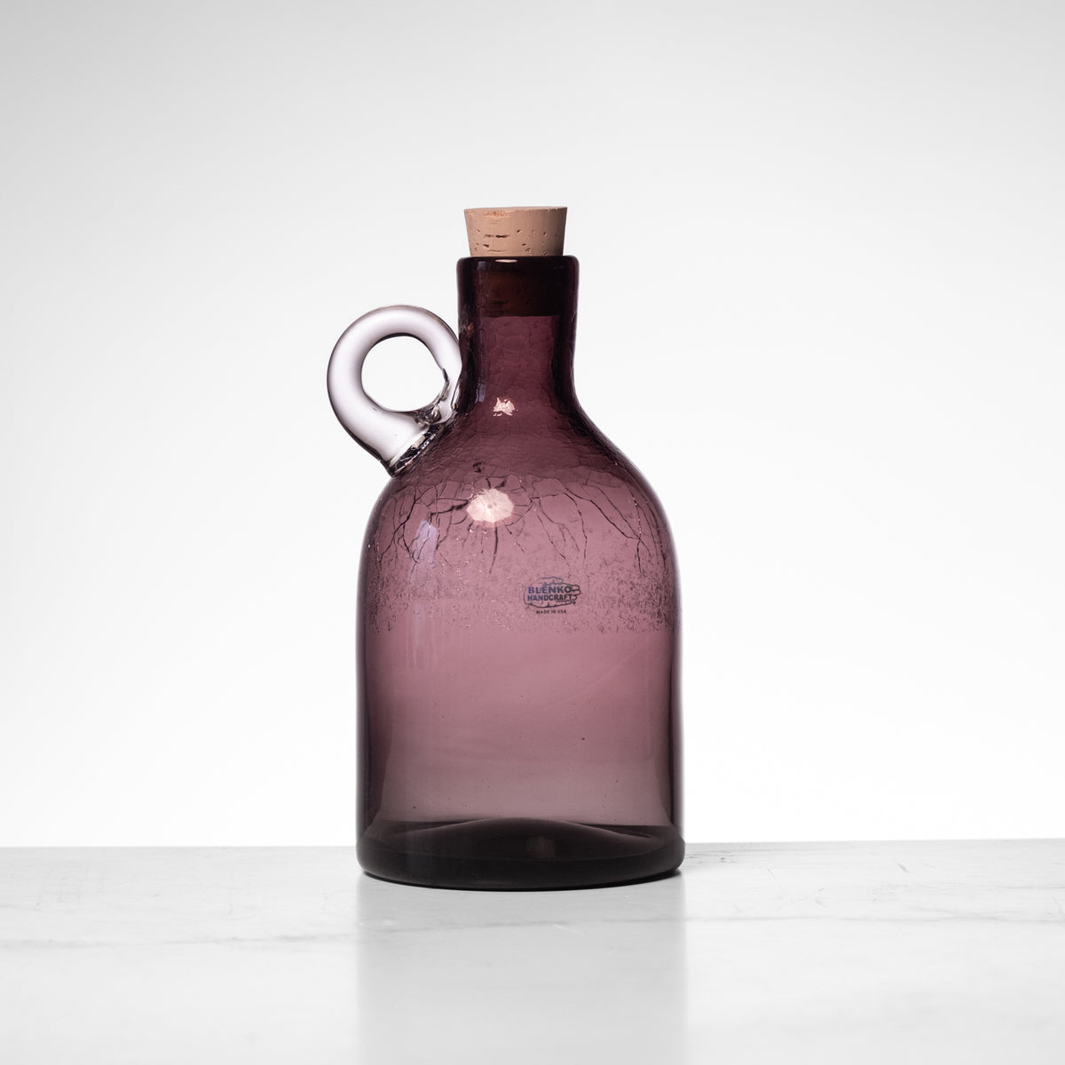 Purple glass bottle with cork on a white background