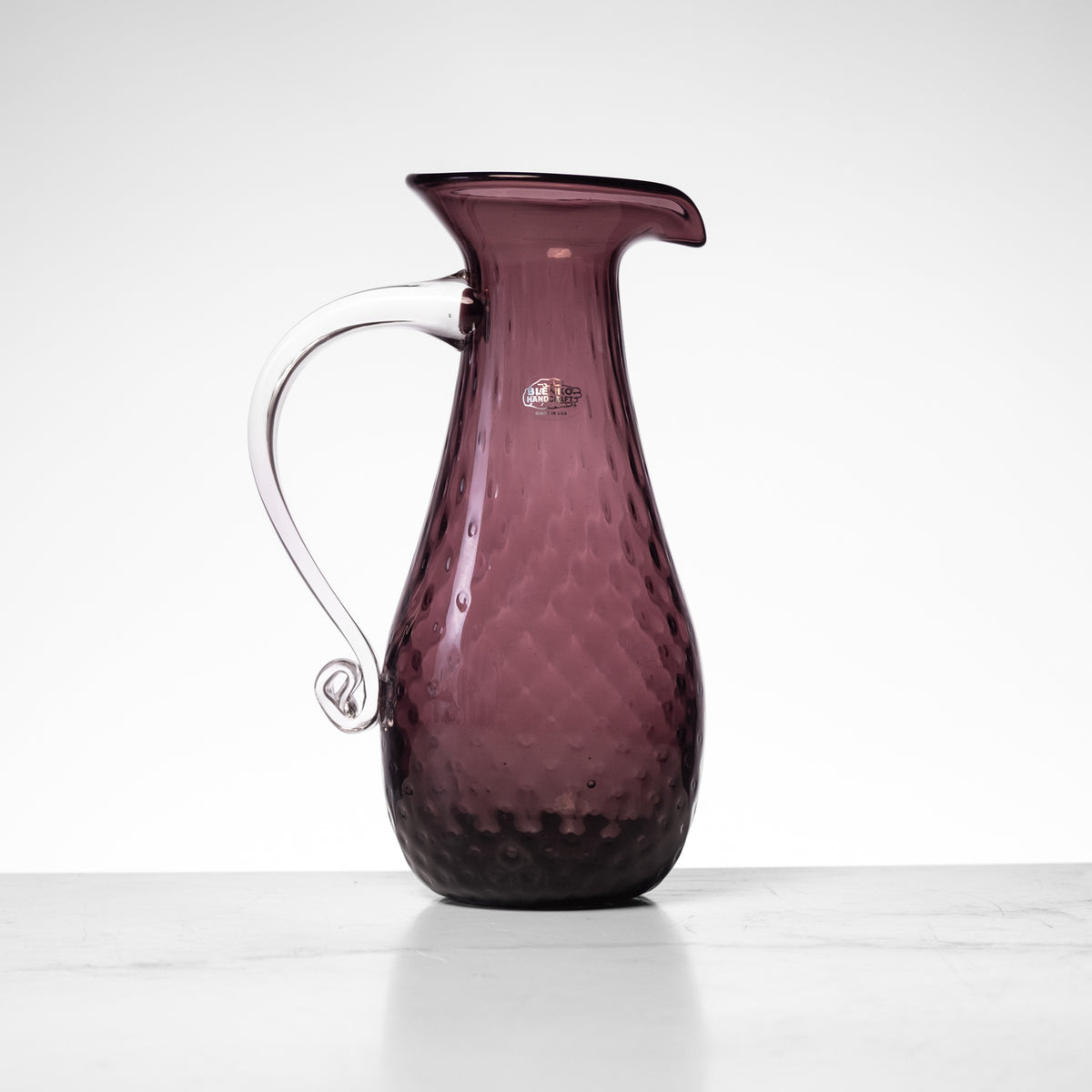 Amethyst glass carafe on a white background