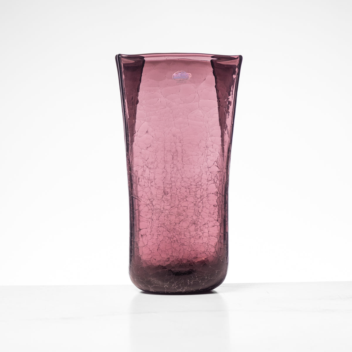 Purple glass vase with textured surface on a white background