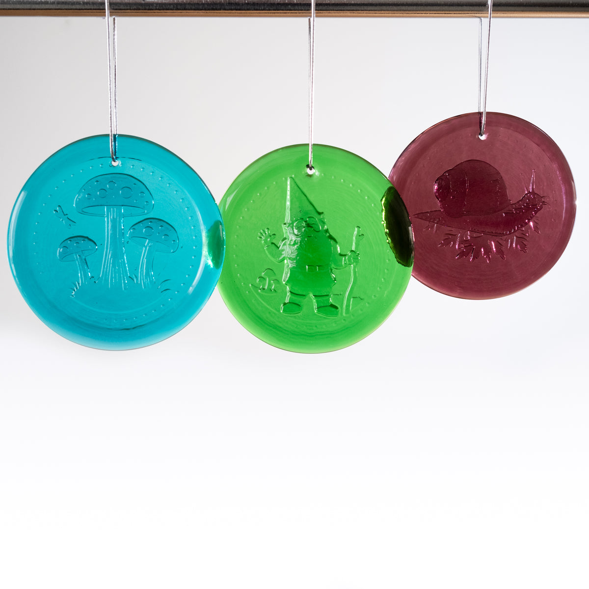 Three colorful round ornaments with embossed designs on a white background