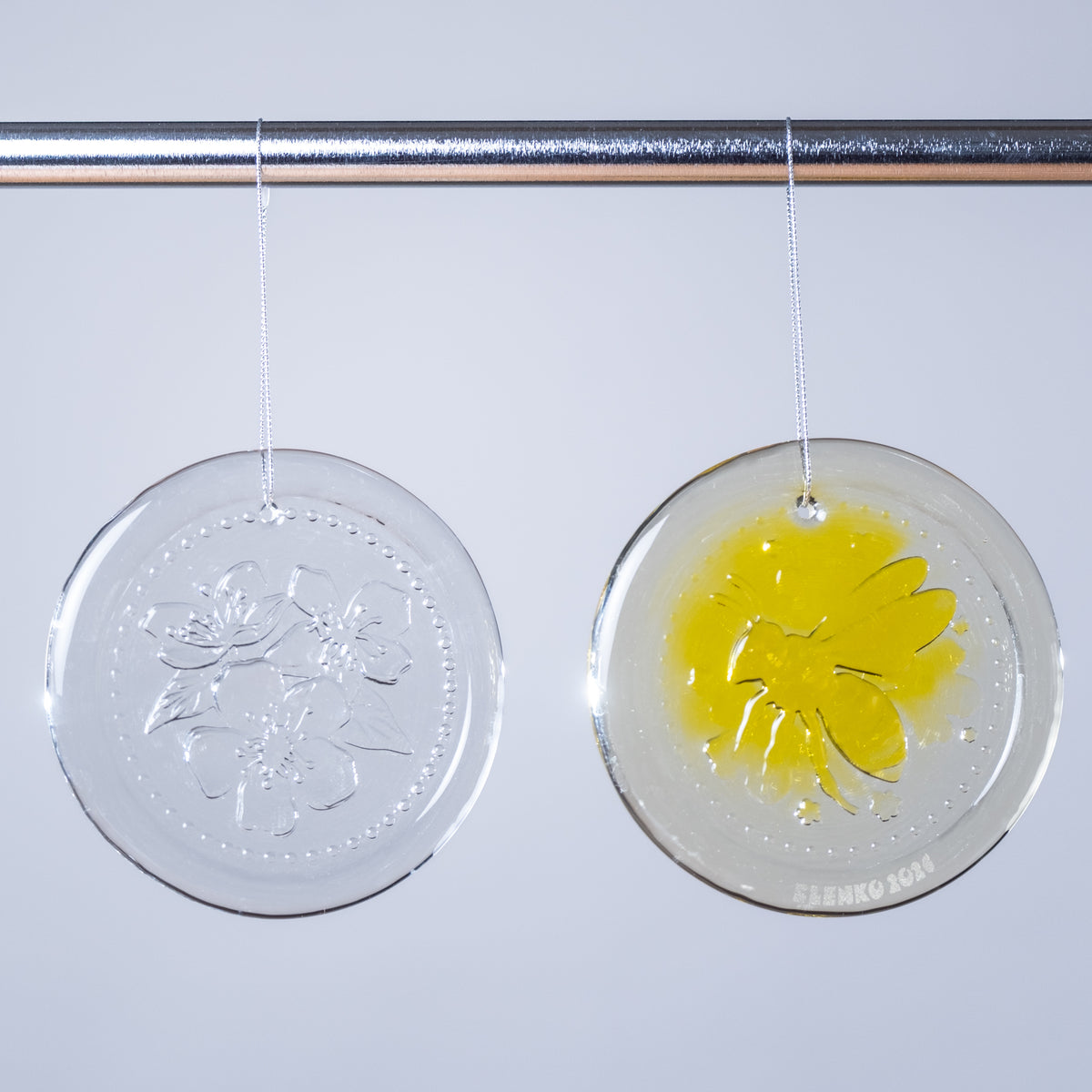Two round clear hanging decorations with floral designs on a white background