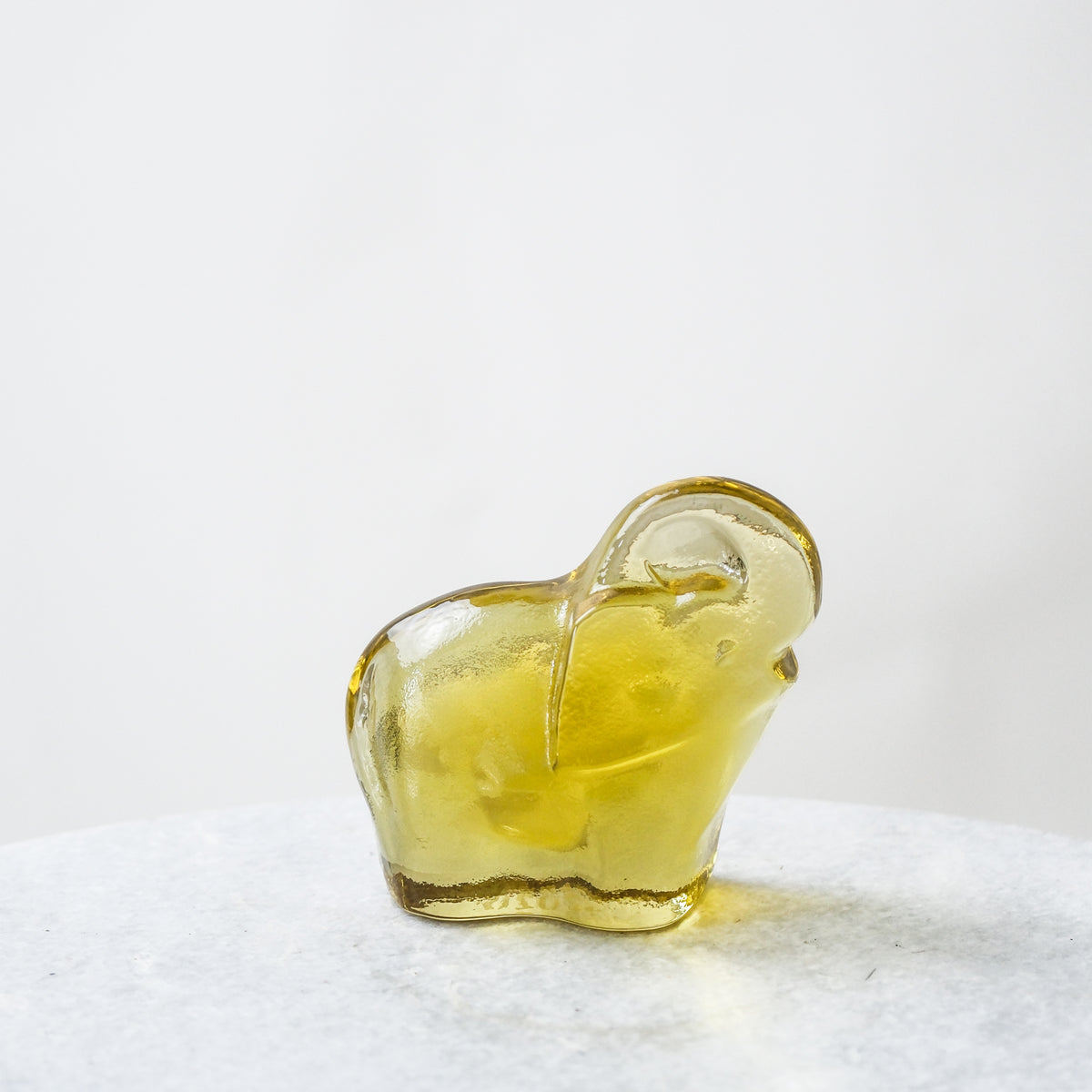 Yellow glass object on a white surface with a white background