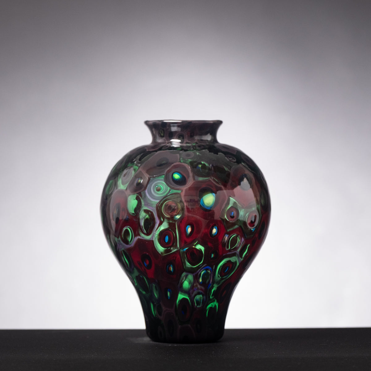 Decorative glass vase with colorful pattern on a gray background