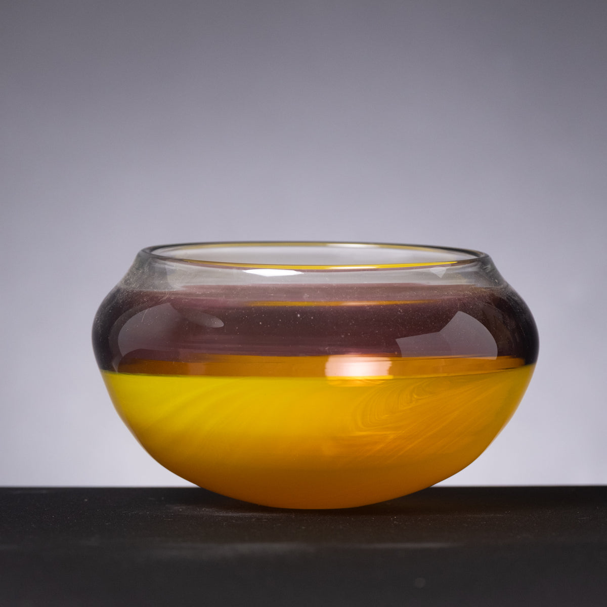 Glass bowl with gradient color from black to yellow on a dark background