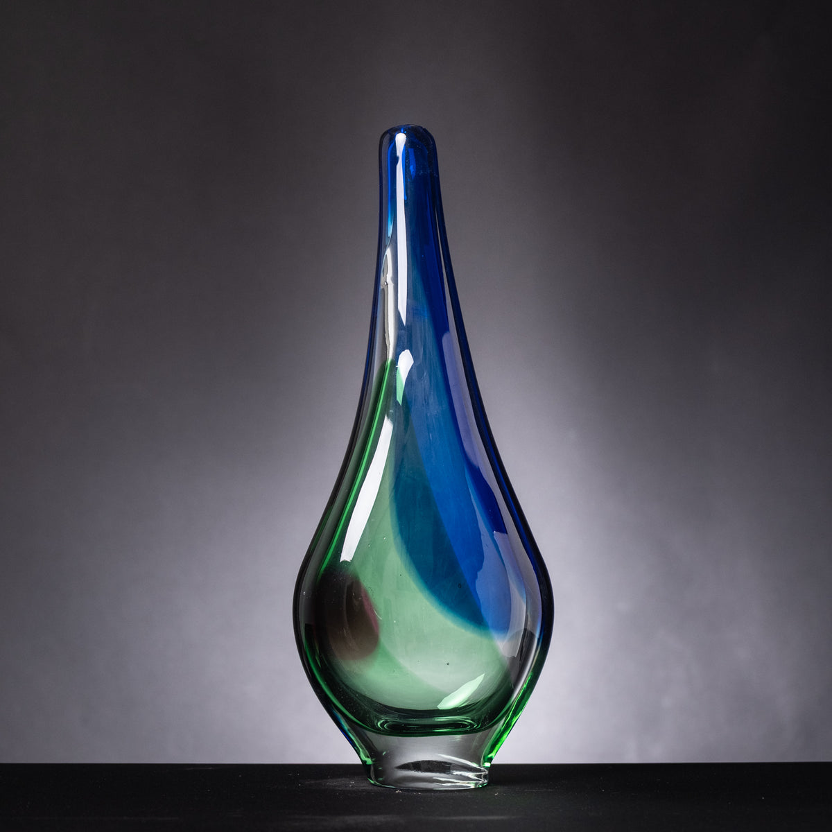Glass vase with blue and green gradient on a dark background