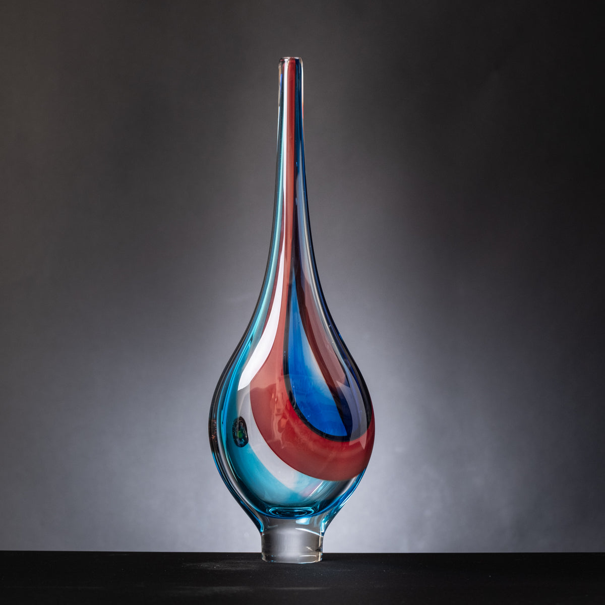 Glass vase with blue and red gradient on a dark background