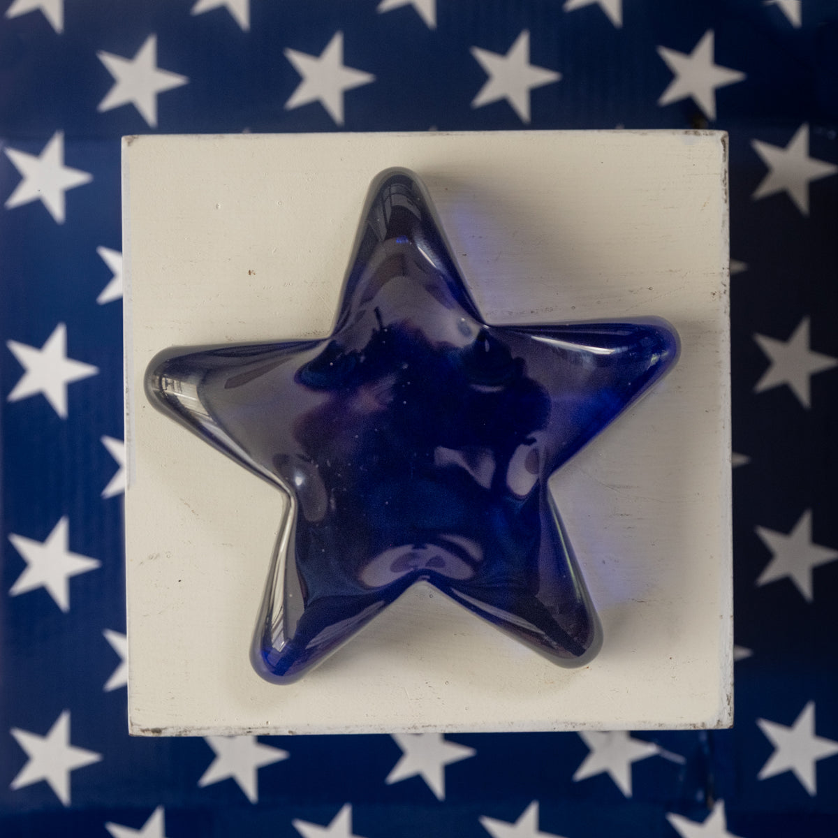 Blue star-shaped object on a white block with a blue background featuring white stars