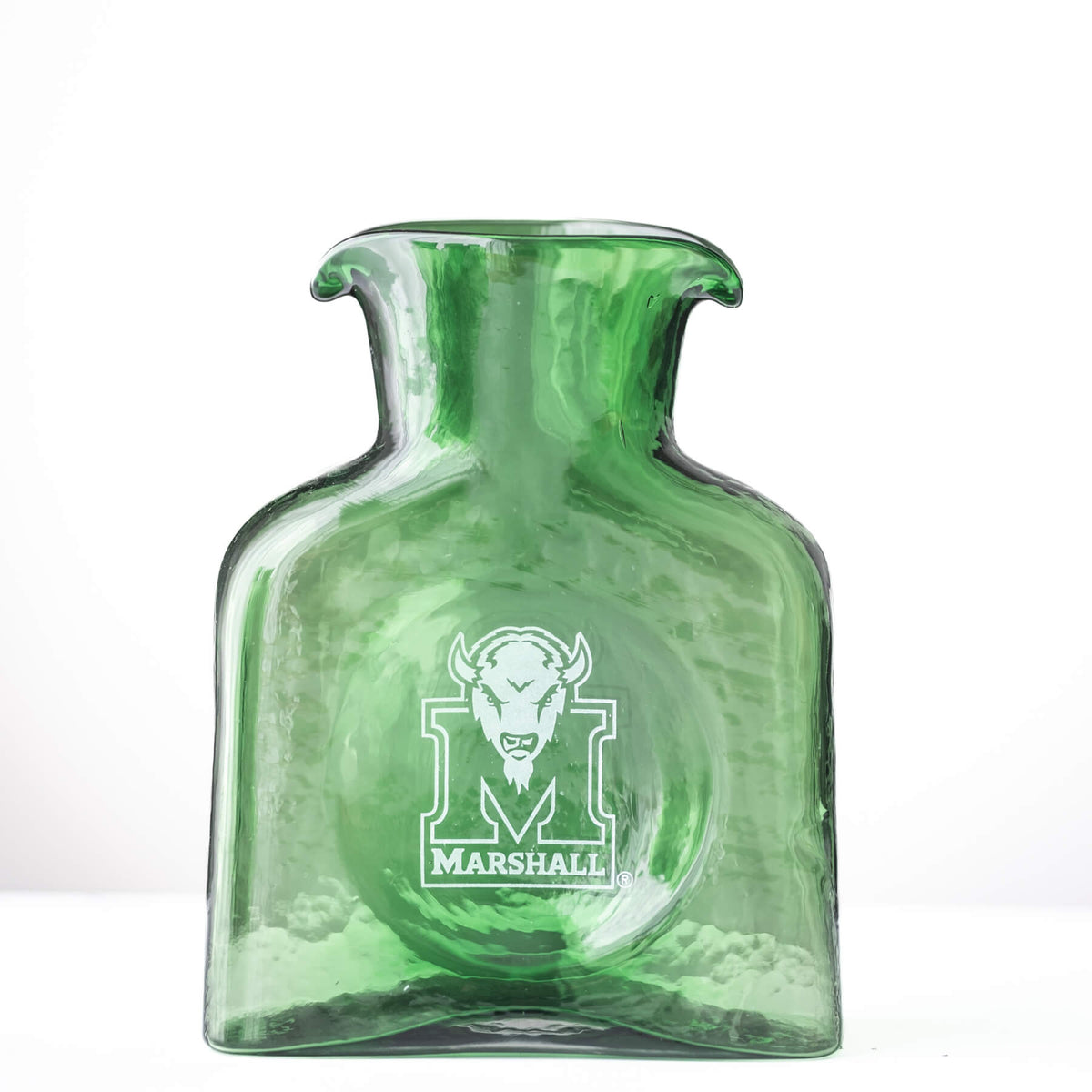 A green glass hot water bottle with a flared neck and a white Marshall logo printed on the front, set against a plain white background.