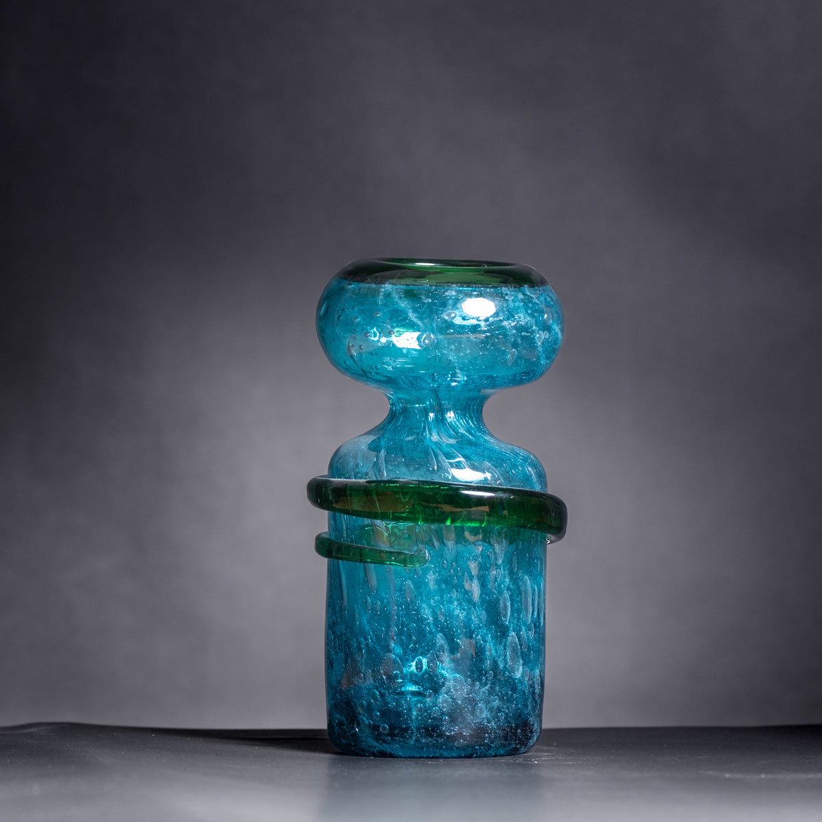 Blue glass vase with textured surface on a gray background