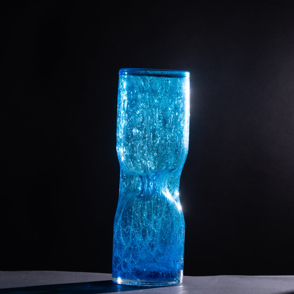 Blue textured glass vase on a black background