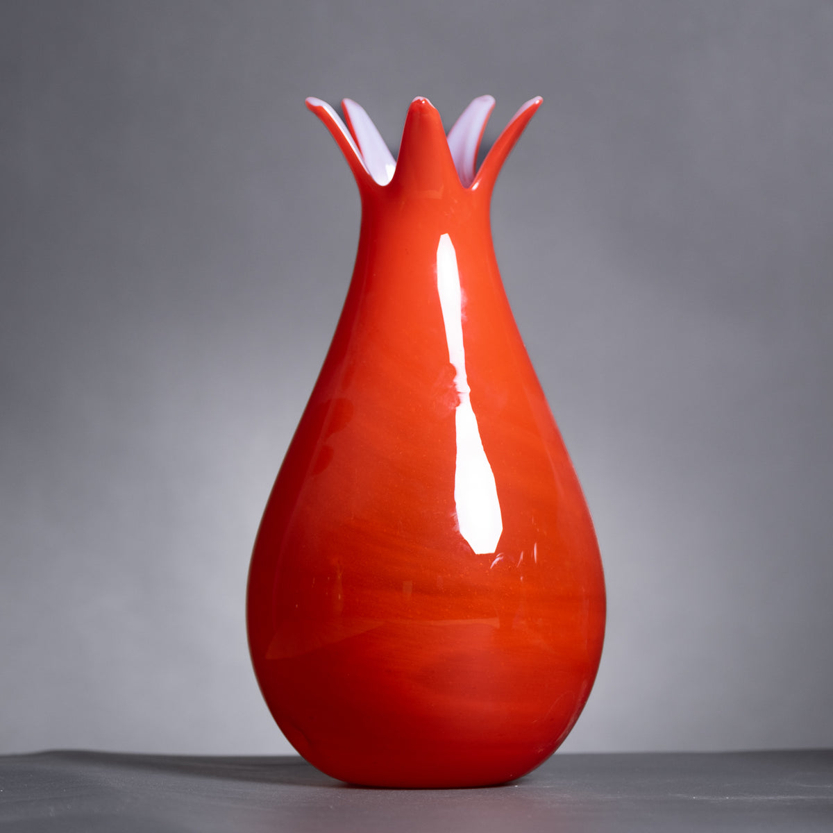 Red ceramic vase with a unique design on a gray background