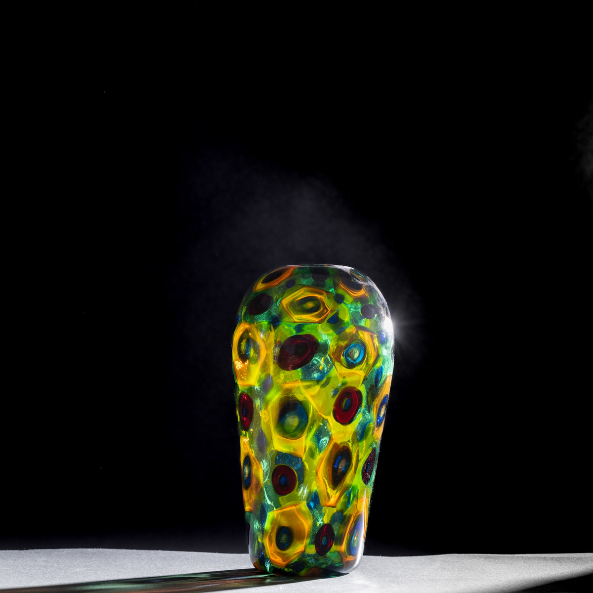 Colorful glass vase with circular patterns on a black background