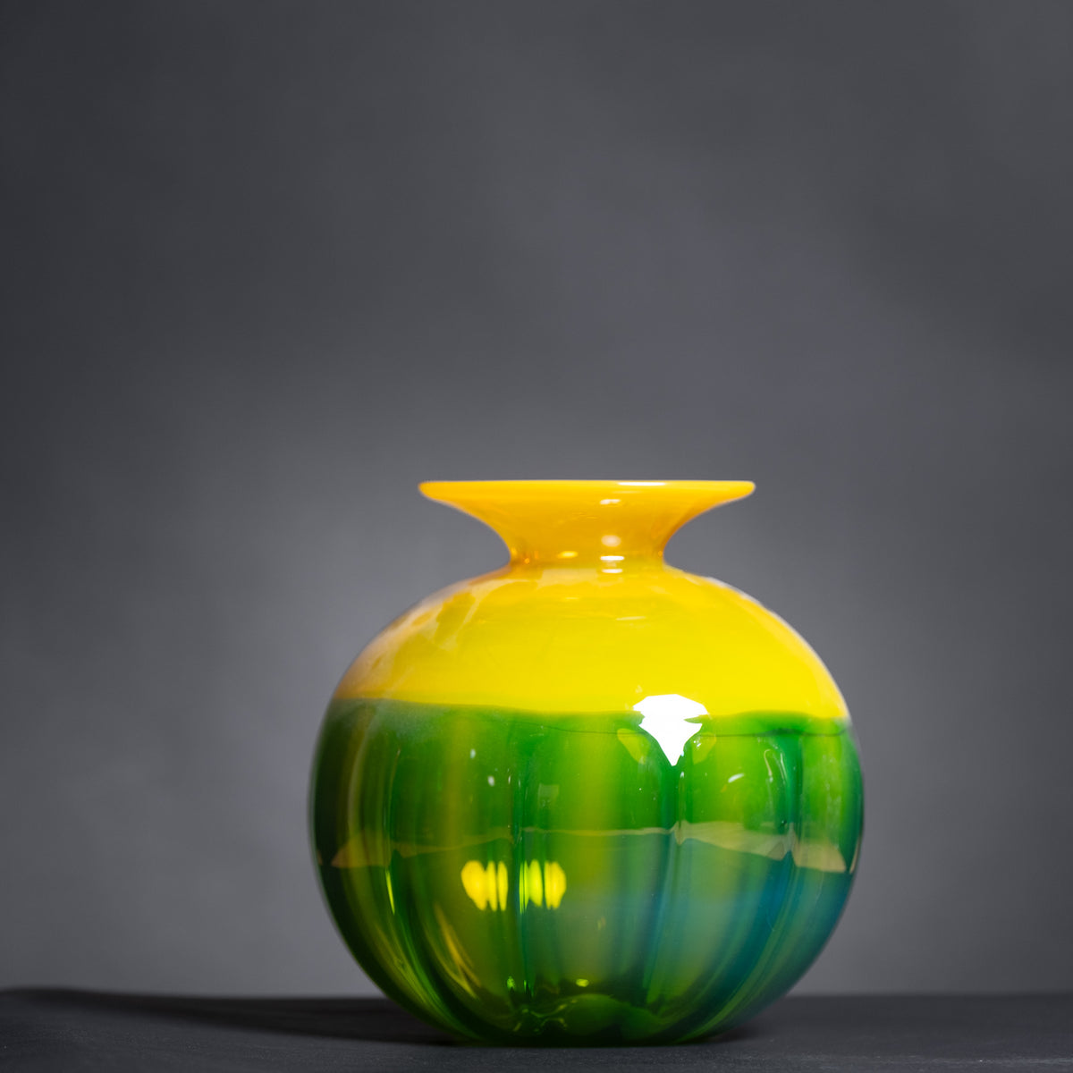 Yellow and green glass vase on a dark background