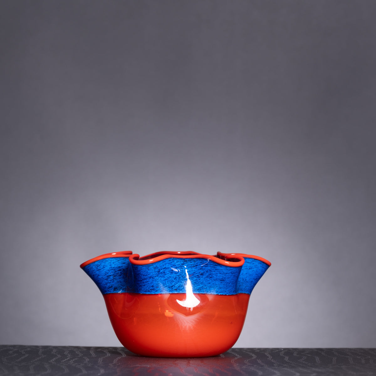 Red and blue ceramic bowl on a textured surface with a gray background