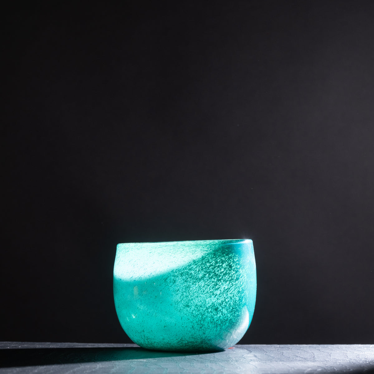 Turquoise glass bowl on a dark background