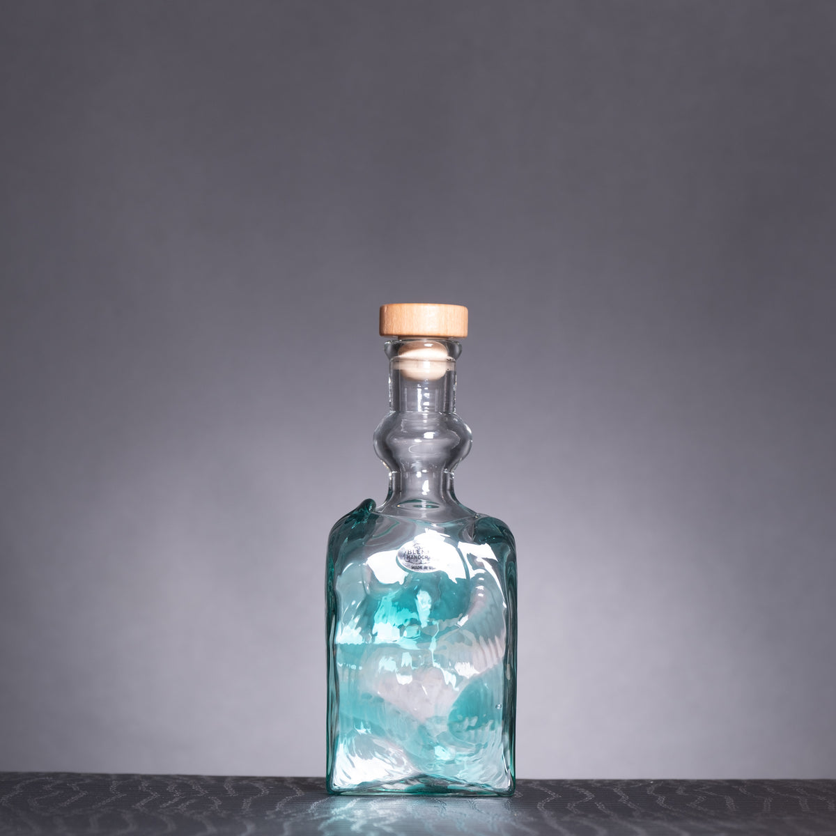 Glass bottle with a wooden cap on a gray background