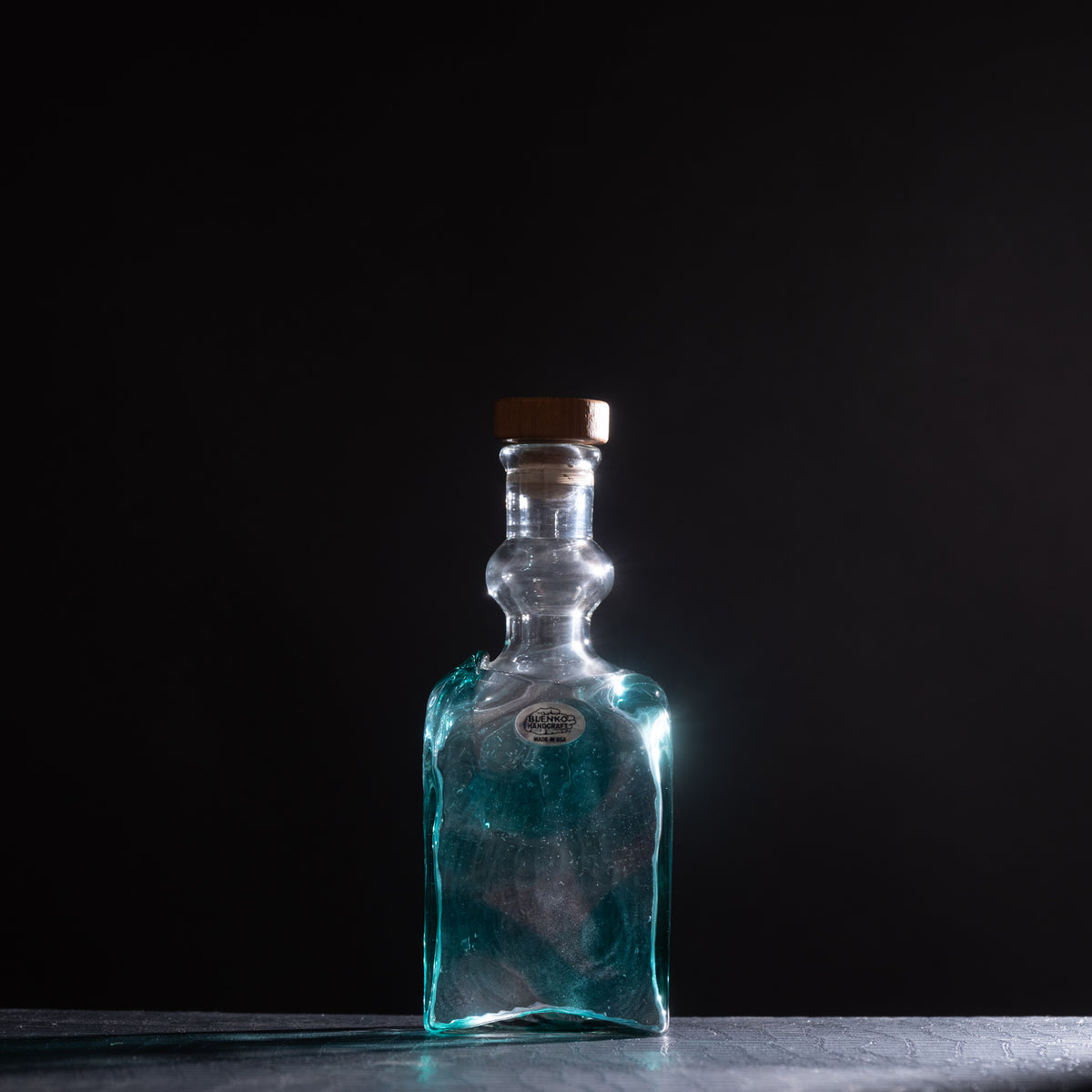 Clear glass bottle with a wooden cap on a dark background
