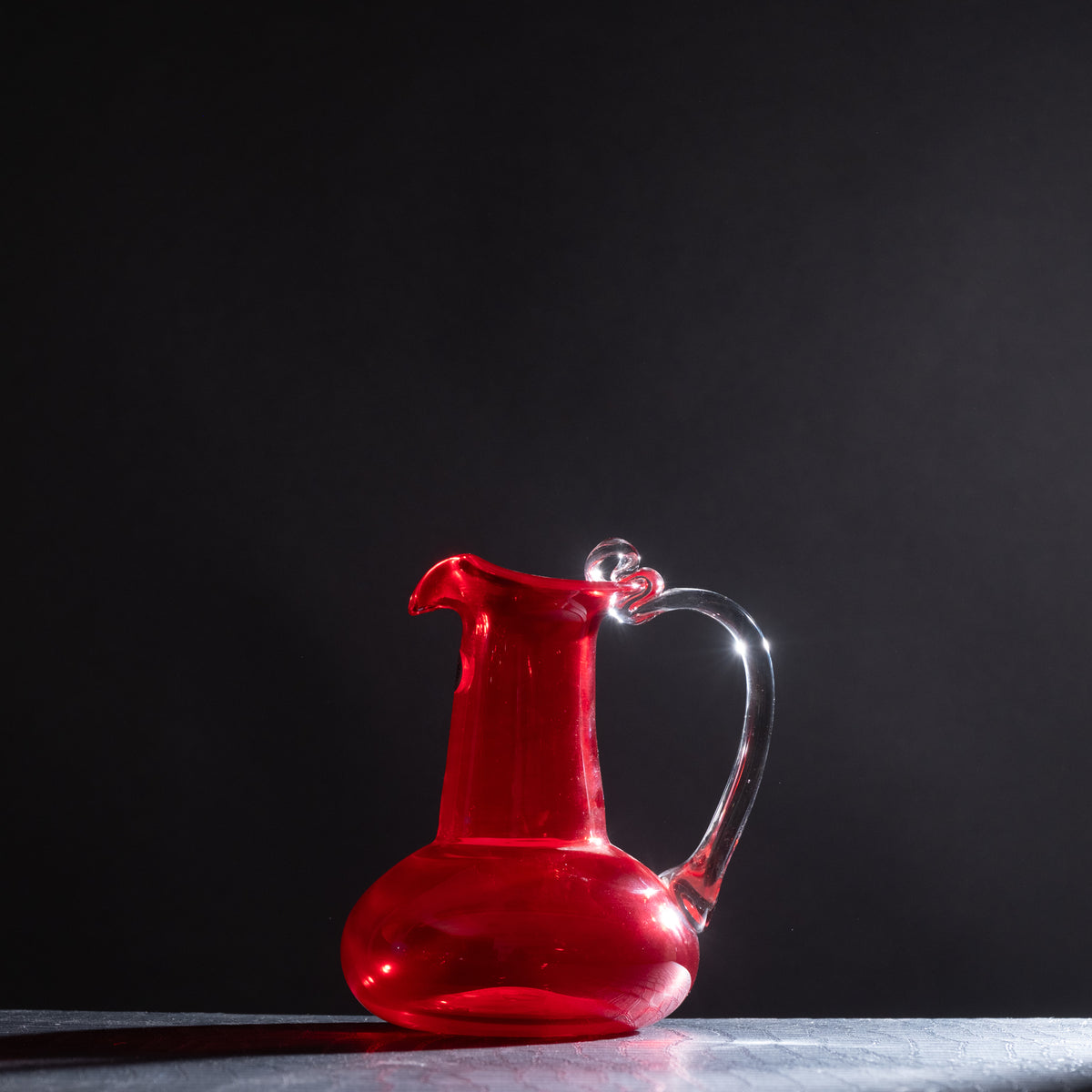 Red glass pitcher on a dark background