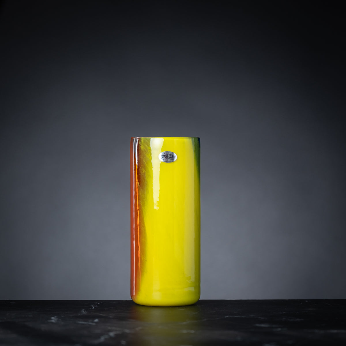 Yellow vase with a reflective surface on a dark background