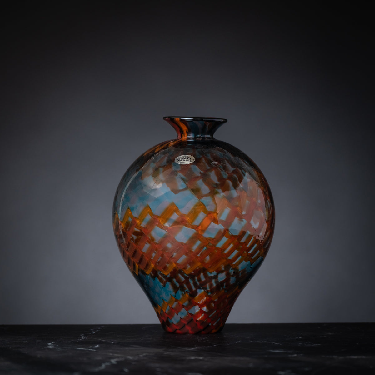Colorful glass vase on a dark surface with a gray background