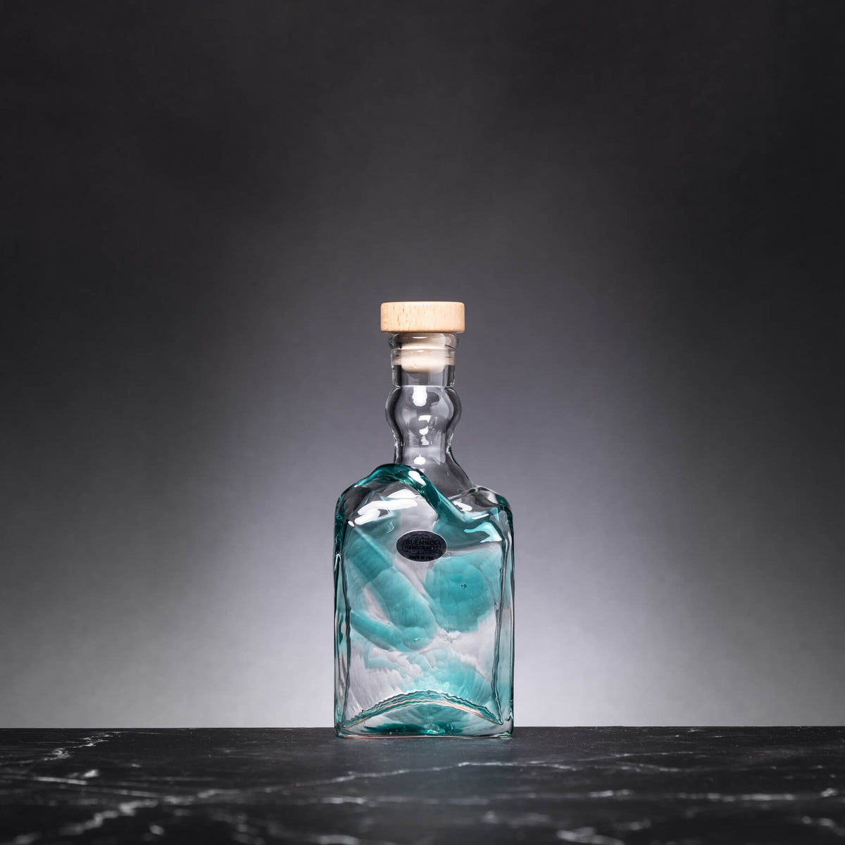 Glass bottle with a cork on a dark surface and gray background