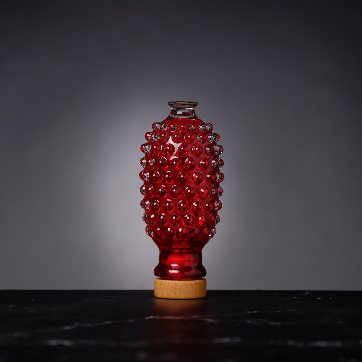 Red textured vase on a dark surface with a gray background