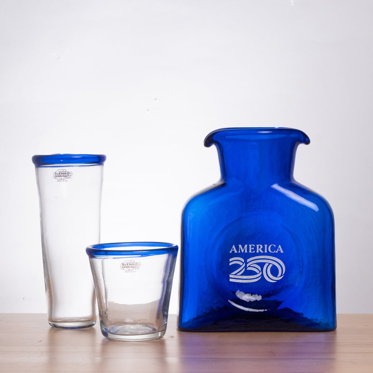 Set of blue and clear glassware with 'America 250' branding on a white background