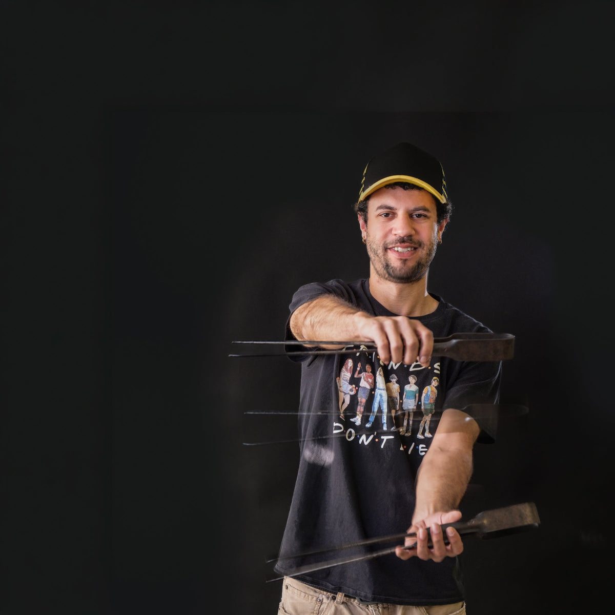 Man holding a bow and arrow against a black background