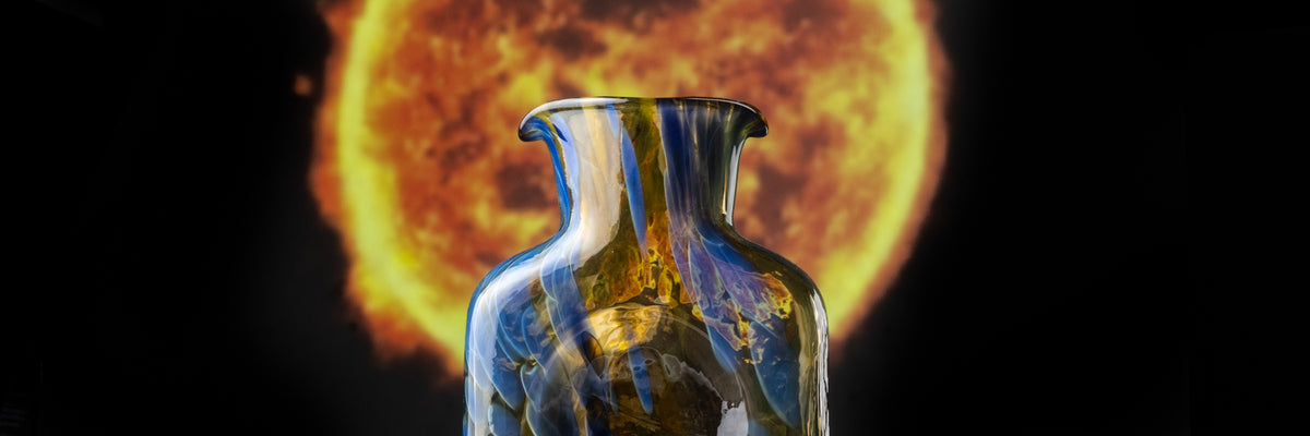 small 384 water bottle colored with blue frit in front of a photo of the sun.
