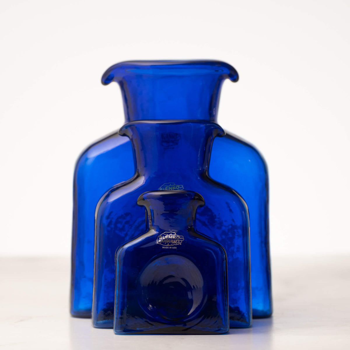 Two blue glass bottles stacked on a white background