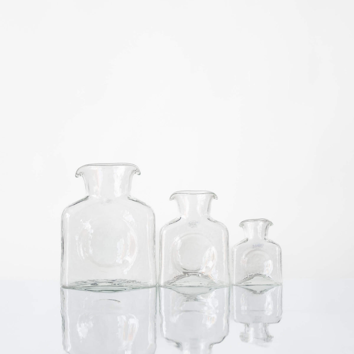 Three clear glass vases of different sizes on a white background