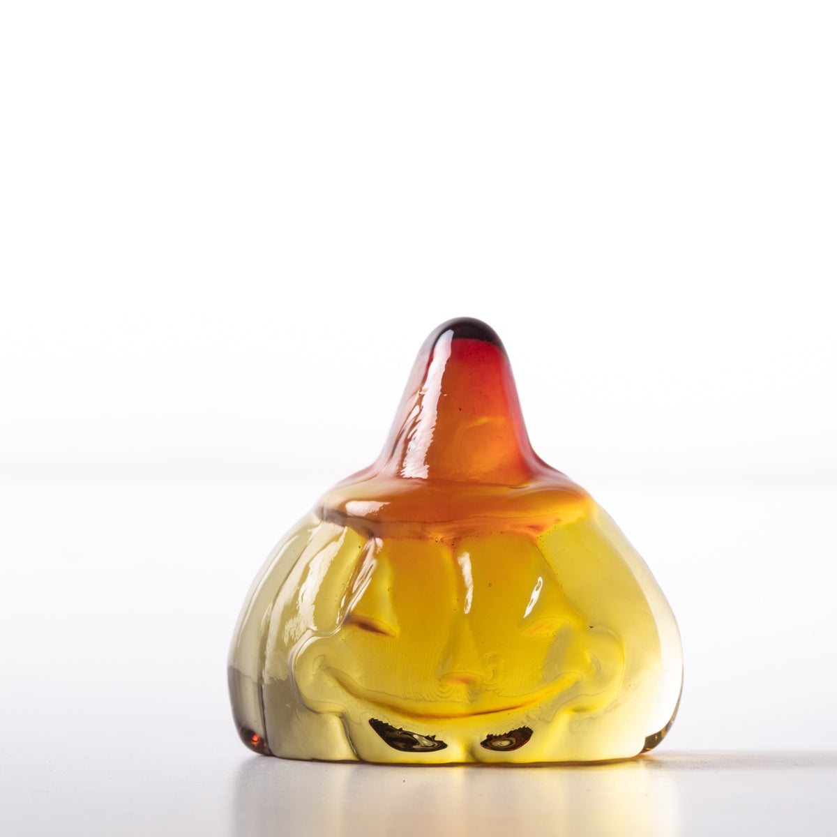 Glass pumpkin figurine with a smiling face on a white background