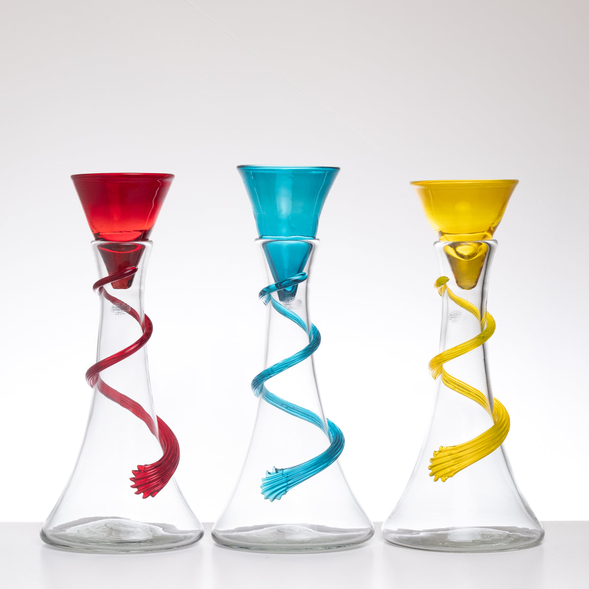 Three colorful glass vases with spiral designs on a white background