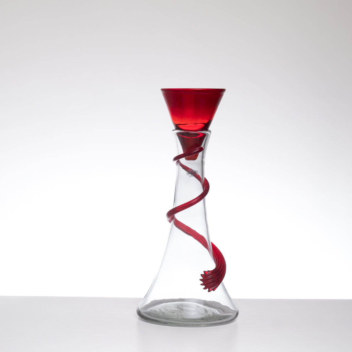 Glass decanter with red spiral design on a white background