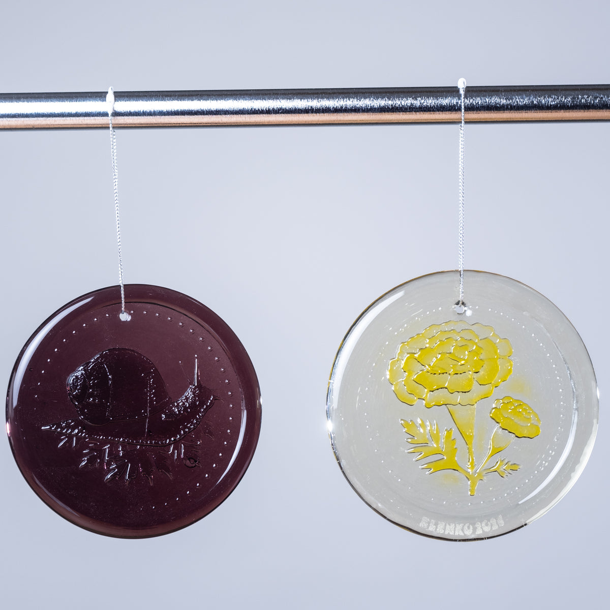 Two round decorative items with floral designs, one purple and one yellow, on a white background.