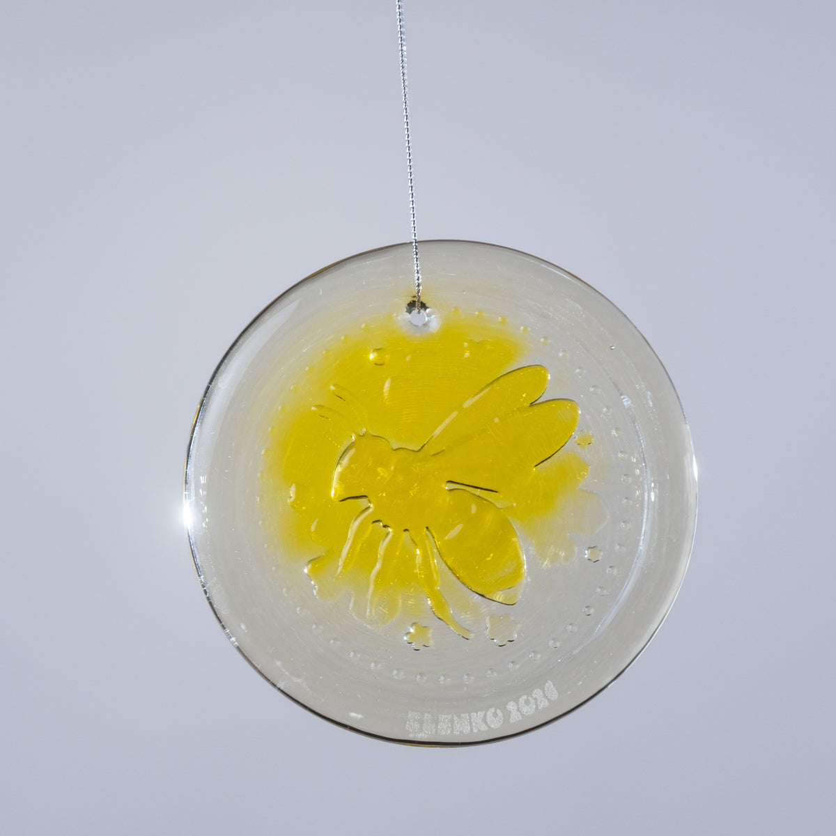 Round decorative item with yellow butterfly design on a white background