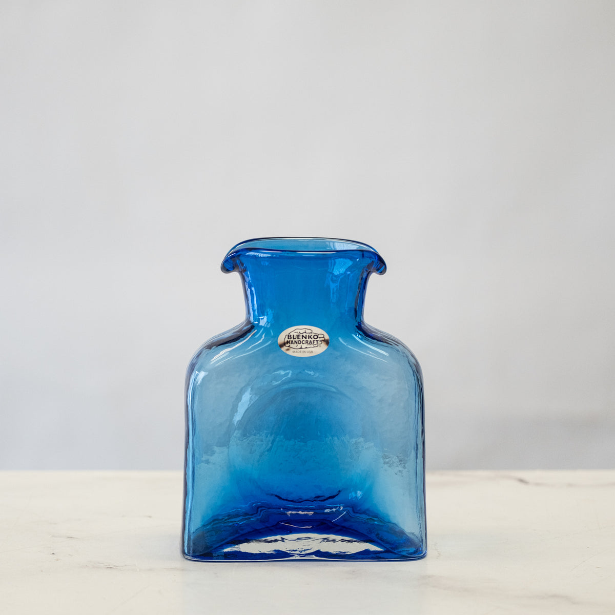 Blue glass vase on a white surface with a light gray background