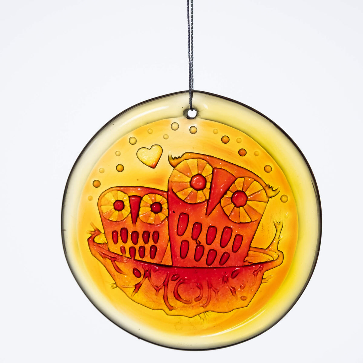 A handcrafted glass suncatcher with a owl family design, in orange and yellow hues, hanging by a string