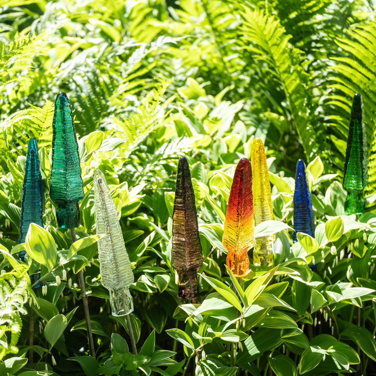 Colorful glass sculptures among green foliage