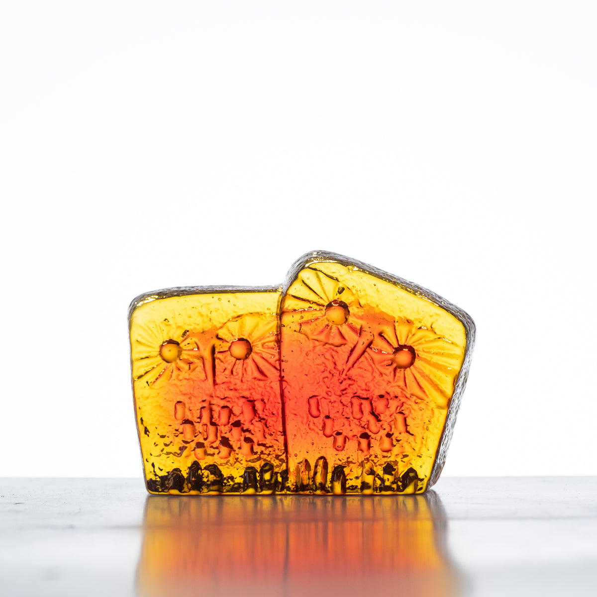 A handcrafted glass figurine with a tangerine color, featuring an owl family design, on a flat surface.