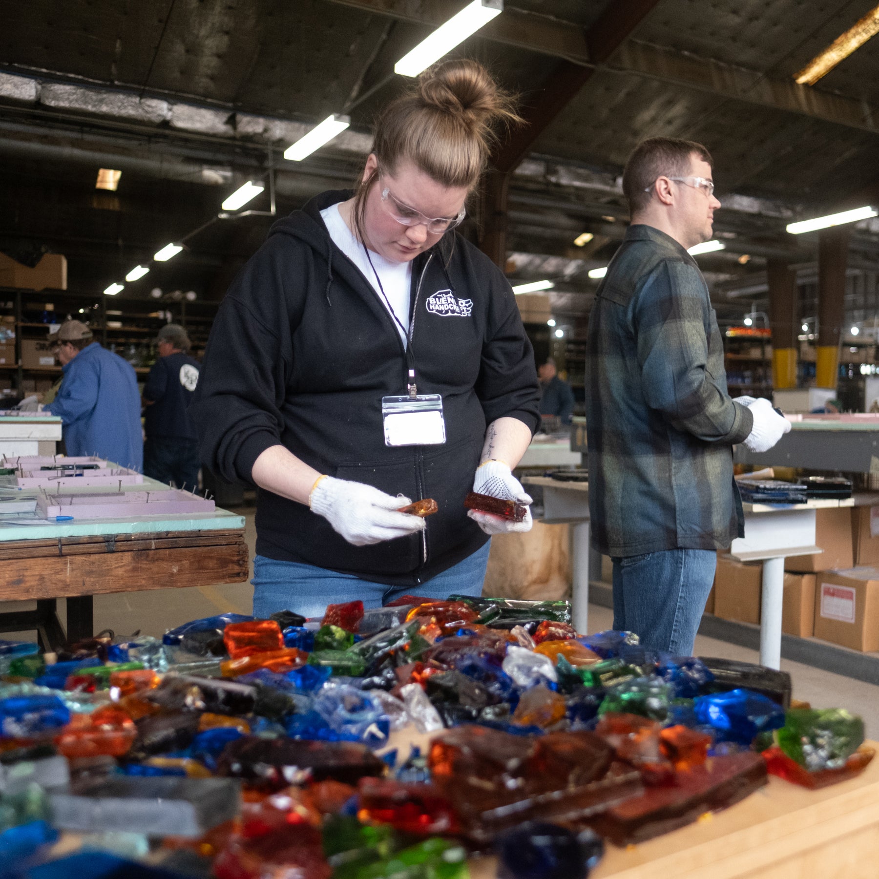 Person working with colorful glass pieces in a workshop setting