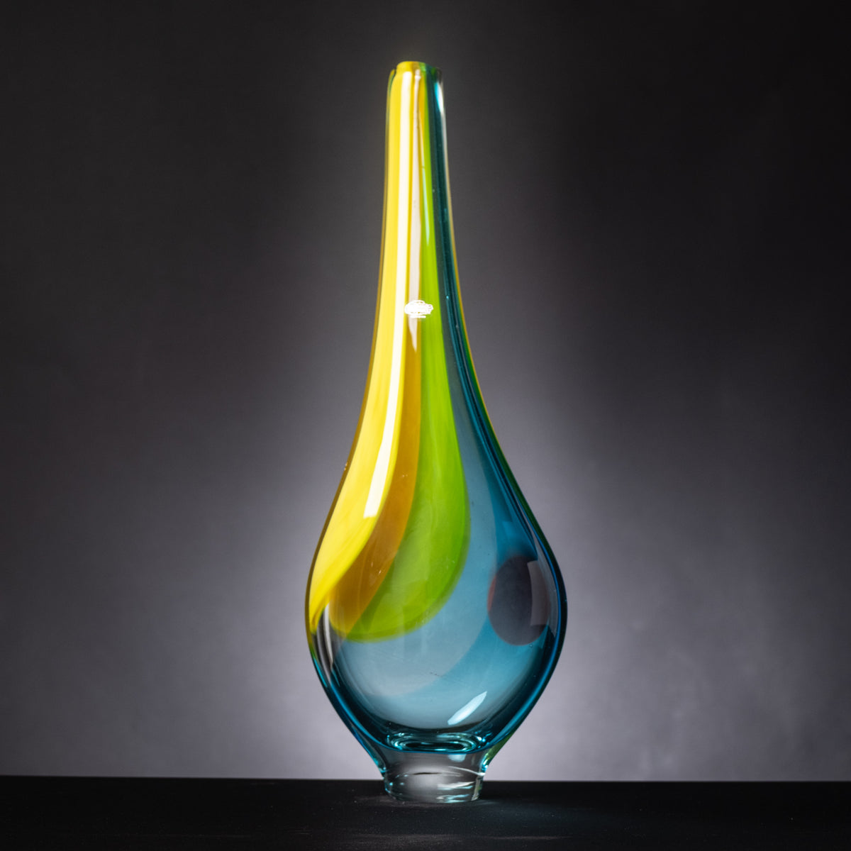 Glass vase with blue, yellow, and green colors on a dark background