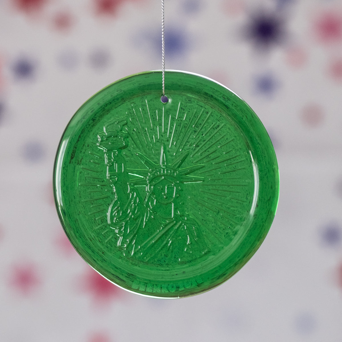 Green circular ornament with textured surface on a blurred background