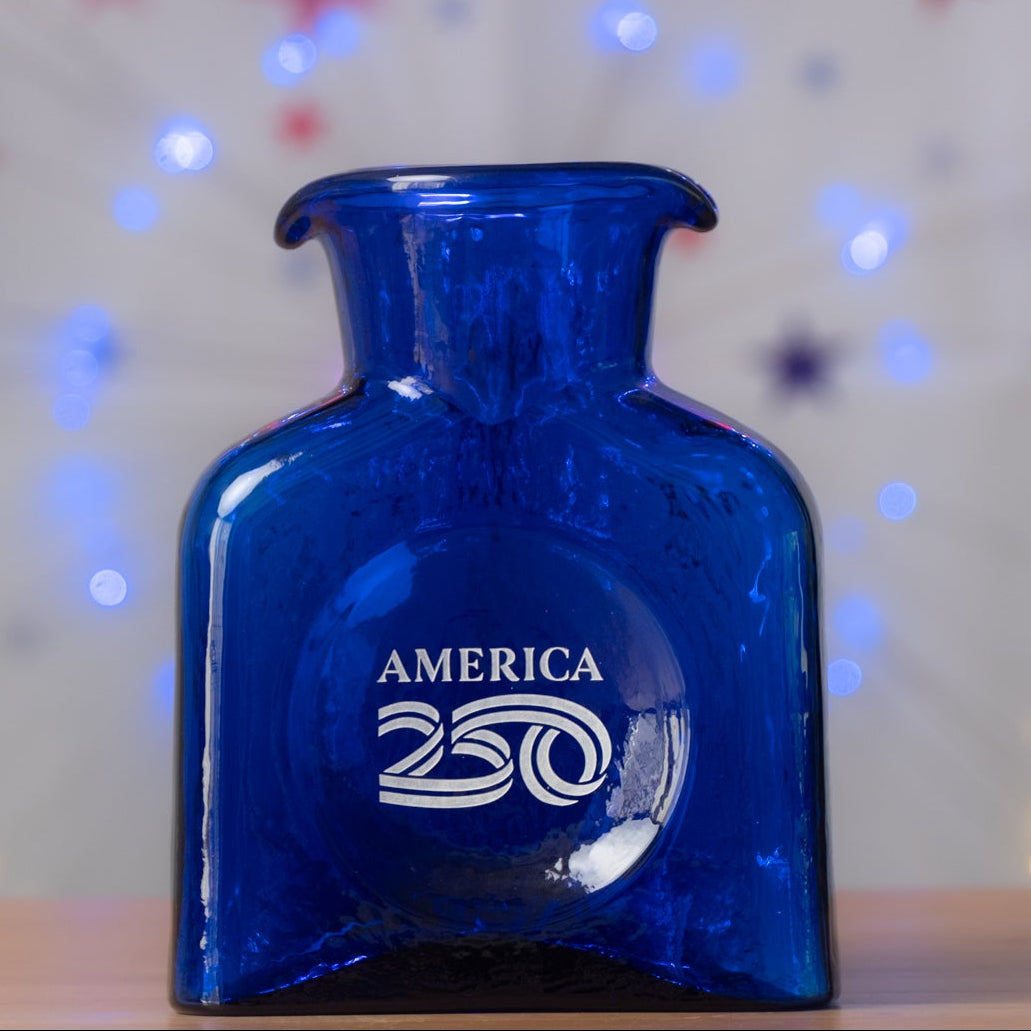 Blue bottle labeled 'America 250' with festive lights in the background