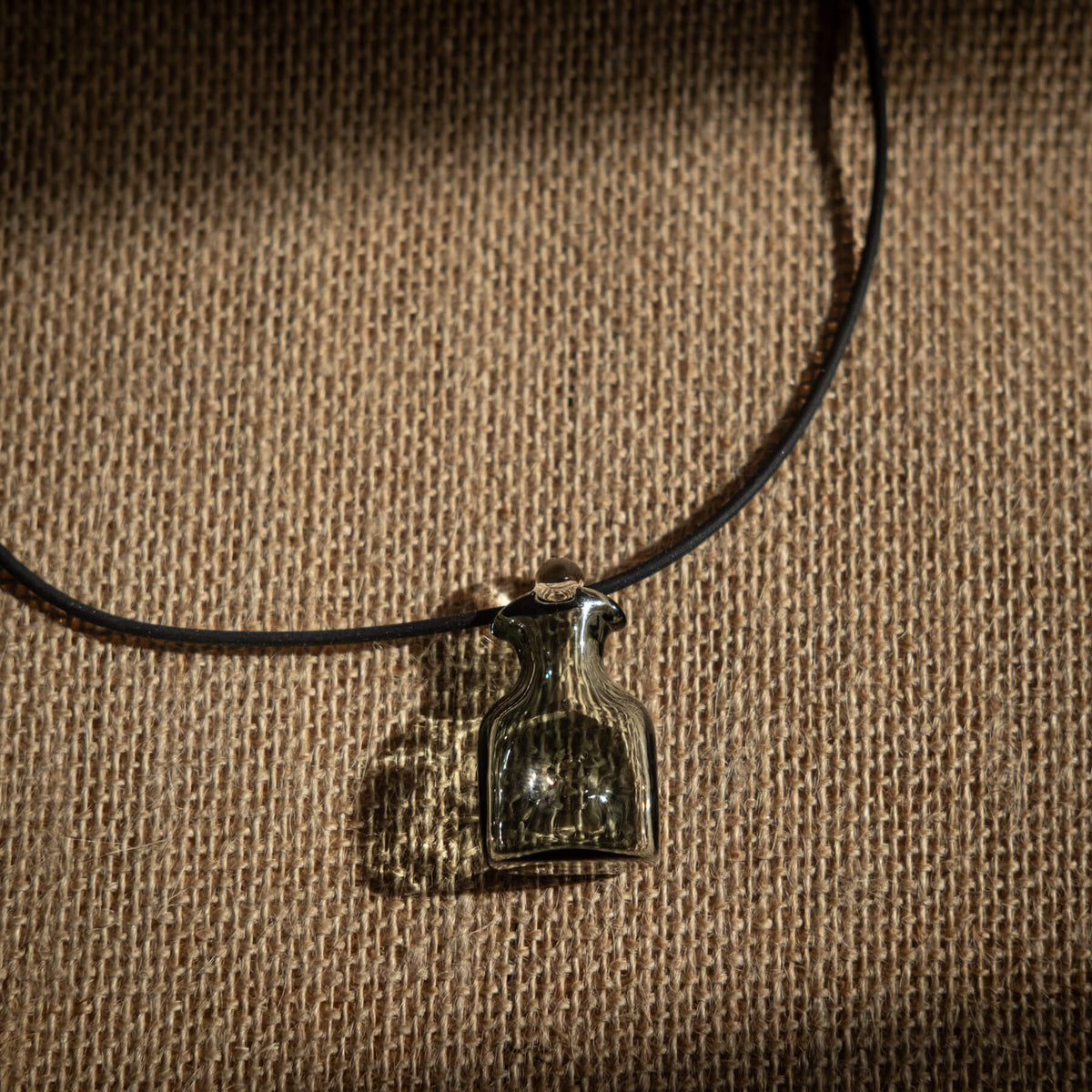 Necklace with a bottle pendant on a brown textured background